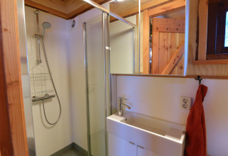 Baño moderno con ducha y lavabo en una casa del árbol en Camping de Koeksebelt, Países Bajos.