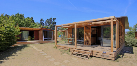 Cabañas de madera con terrazas en Camping d'Angers - Lac de Maine, en Centre-Val de Loire, Francia, día soleado.