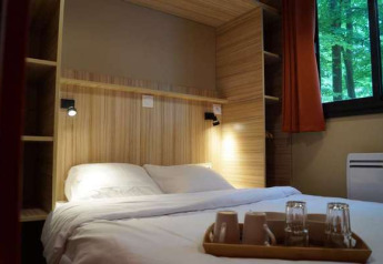 Schlafzimmer im Chalet Evasion, Camping d'Angers - Lac de Maine, mit Doppelbett und Waldblick.