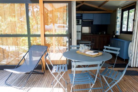 Terrasse mit Tisch und Stühlen vor Chalet Evasion im Camping d'Angers - Lac de Maine, Frankreich.