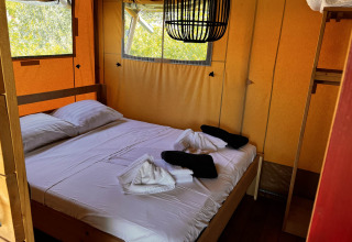 Interior de tienda glamping safari con cama doble y ventanas en Per Amore del Vino, Italia.