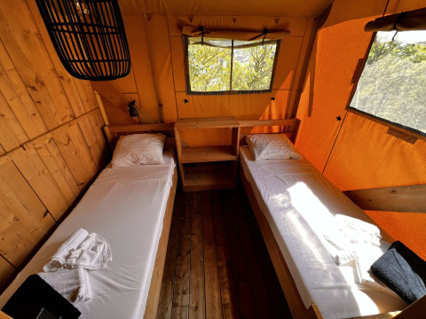 Interior de una tienda glamping safari en Per Amore del Vino, Italia, con dos camas individuales y ventanas grandes.