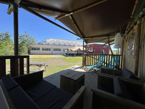 Vista desde una terraza de tienda safari en Glamping tent Per Amore del Vino, Italia, con muebles y áreas verdes.