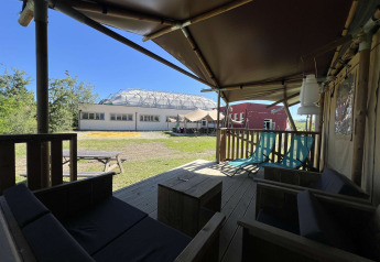 Vista desde una terraza de tienda safari en Glamping tent Per Amore del Vino, Italia, con muebles y áreas verdes.