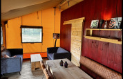 Interior acogedor de una tienda safari glamping en Per Amore del Vino, Italia, con muebles rústicos de madera.