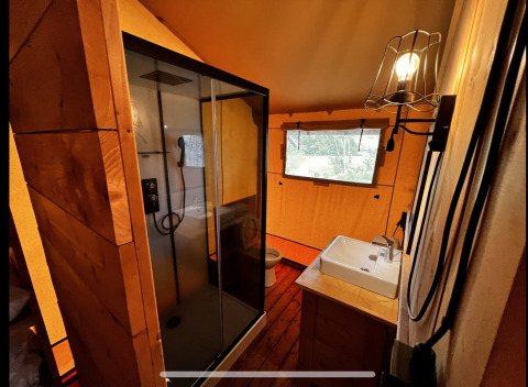 Baño dentro de una tienda glamping en Per Amore del Vino, Italia, con ducha, lavabo y ventana.