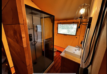 Baño dentro de una tienda glamping en Per Amore del Vino, Italia, con ducha, lavabo y ventana.