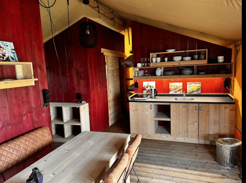 Vista interior de una tienda glamping de lujo con cocina y comedor en Per Amore del Vino, Italia.