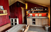 Vista interior de una tienda glamping de lujo con cocina y comedor en Per Amore del Vino, Italia.