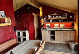 Vista interior de una tienda glamping de lujo con cocina y comedor en Per Amore del Vino, Italia.