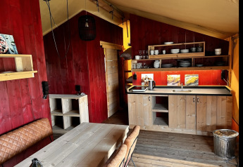 Vista interior de una tienda glamping de lujo con cocina y comedor en Per Amore del Vino, Italia.