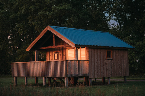 Chalet en bois avec toit bleu au coucher du soleil à la Wellness lodge d'Ackerlodges Ruinerwold BV aux Pays-Bas.