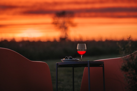 Zonsondergang bij Wellness lodge bij Ackerlodges Ruinerwold BV in Nederland met wijn en snacks op tafel.