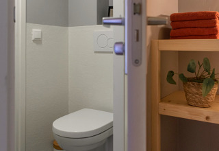 Modern restroom with wall-mounted toilet, gray walls and towels inside the Wellness Lodge Ackerlodges.
