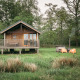 Wellness lodge con chalet in legno, veranda, sedie arancioni e vasca idromassaggio immersa nel verde.