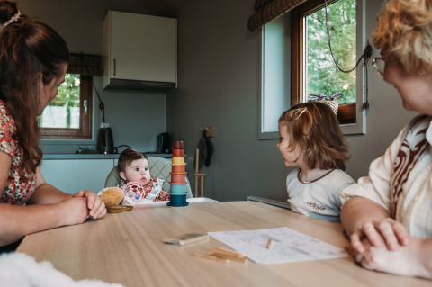 Familie sidder omkring et bord i Wellness lodge ved Ackerlodges Ruinerwold BV i Holland, med børn til stede.