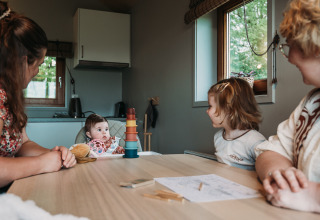 Familie aan een tafel in de Wellness lodge bij Ackerlodges Ruinerwold BV in Nederland met kinderen erbij.