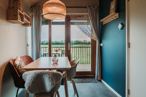 Sfeervolle eetruimte met uitzicht op weide in Wellness lodge van Ackerlodges Ruinerwold BV, Nederland.