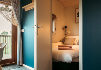 Ingang van een wellness lodge-kamer bij Ackerlodges Ruinerwold BV in Nederland met bed en balkon.