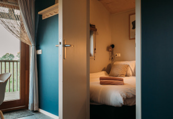 Entrée d'une chambre de lodge bien-être à Ackerlodges Ruinerwold BV aux Pays-Bas, avec lit et balcon.