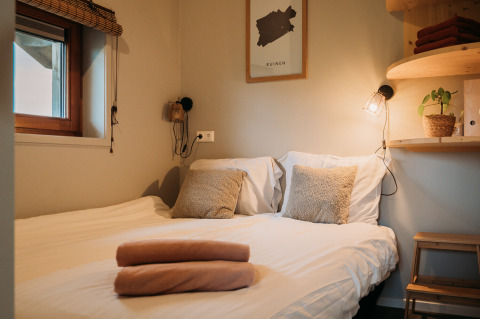 Acogedora cama doble con almohadas suaves y luz cálida en Wellness lodge en Ackerlodges Ruinerwold BV, Países Bajos.