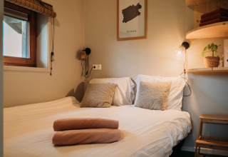 Acogedora cama doble con almohadas suaves y luz cálida en Wellness lodge en Ackerlodges Ruinerwold BV, Países Bajos.