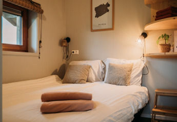 Acogedora cama doble con almohadas suaves y luz cálida en Wellness lodge en Ackerlodges Ruinerwold BV, Países Bajos.