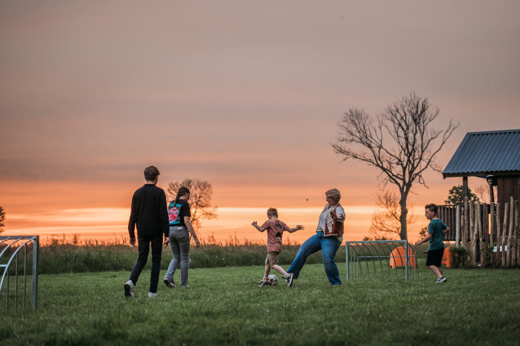 Personas juegan fútbol en un campo de césped al atardecer cerca de Wellness Lodge en Ackerlodges Ruinerwold BV en los Países Bajos.