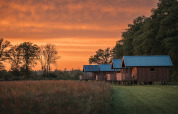 Wellness lodge at Ackerlodges Ruinerwold BV in the Netherlands with wooden cabins and a stunning sunset.