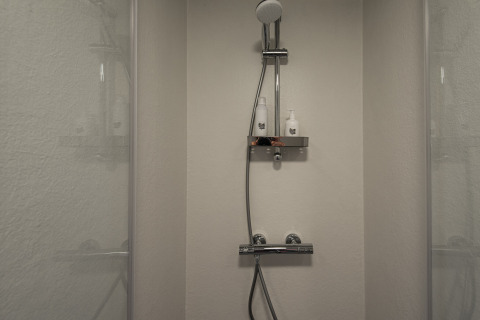Ducha moderna en Wellness Lodge, Ackerlodges Ruinerwold BV en Países Bajos, con dos botellas en el estante.