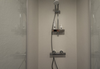 Ducha moderna en Wellness Lodge, Ackerlodges Ruinerwold BV en Países Bajos, con dos botellas en el estante.