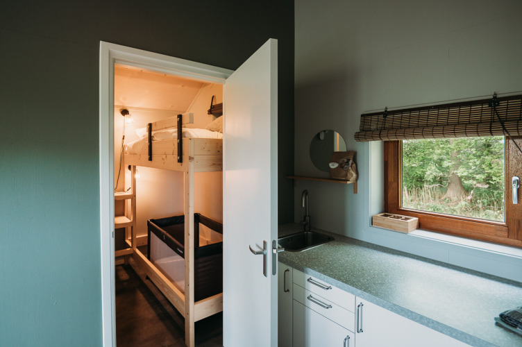 Interior moderno de cabaña con cocina y litera en Wellness Lodge de Ackerlodges Ruinerwold BV, Países Bajos.