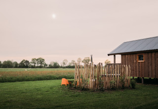 Lodge de bienestar en Ackerlodges Ruinerwold BV, Países Bajos, con cabaña de madera y campo verde.