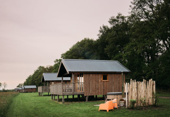Hyggelige wellness-lodges hos Ackerlodges Ruinerwold BV i Holland, omgivet af grøn natur og træer.