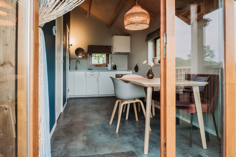 Vista interior de una moderna cabaña de bienestar con comedor y cocina en Ackerlodges Ruinerwold, Países Bajos.