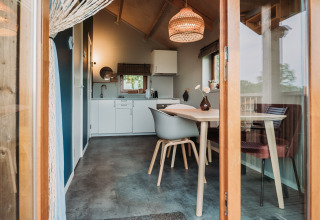 Vista interior de una moderna cabaña de bienestar con comedor y cocina en Ackerlodges Ruinerwold, Países Bajos.