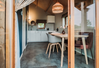 Vista interna di un moderno wellness lodge con zona pranzo e cucina presso Ackerlodges Ruinerwold, Paesi Bassi.