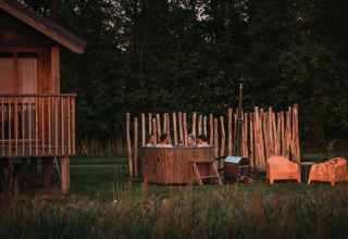 Fire personer slapper af i udendørs spabad ved Wellness Lodge på Ackerlodges Ruinerwold BV, Holland.