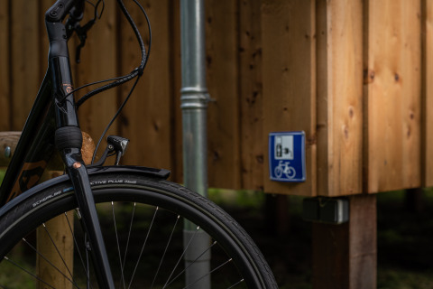 Fahrradvorderrad an der Wellness-Lodge bei Ackerlodges Ruinerwold BV, Niederlande, mit Fahrradservice-Schild.