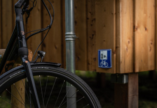 Voorwiel van fiets aan Wellness lodge Ackerlodges Ruinerwold BV in Nederland, met bordje fietsservice.