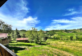 Blick von einem Safarizelt bei Per Amore del Vino in Italien auf grüne Hügel und blauen Himmel.