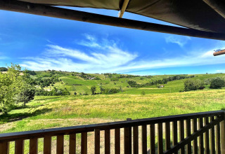 Scenic view from a glamping tent terrace overlooking green vineyards at Per Amore del Vino in Italy.