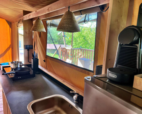 Cocina moderna dentro de una tienda safari glamping en Per Amore del Vino, Italia, con vistas al exterior.