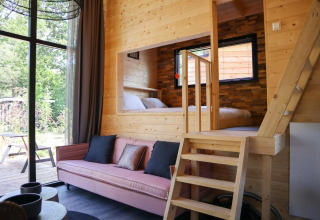 Interieur van een moderne Tiny House lodge bij De Hooge Veluwe met houten inrichting en groot raam.