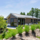 Moderne Velthorst-lodge ved EuroParcs Veluwemeer i Holland, omgivet af grønne planter og blå himmel.