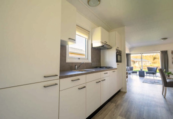 Cucina moderna e luminosa nel lodge Velthorst 4 a Zuiderzee, Paesi Bassi, aperta su soggiorno e giardino.
