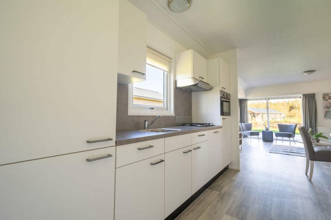 Cucina moderna e luminosa nel lodge Velthorst 4 a Zuiderzee, Paesi Bassi, aperta su soggiorno e giardino.