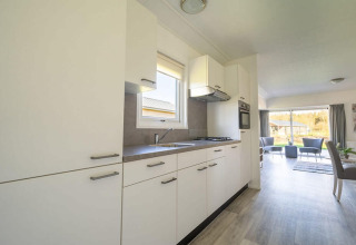 Cucina moderna e luminosa nel lodge Velthorst 4 a Zuiderzee, Paesi Bassi, aperta su soggiorno e giardino.