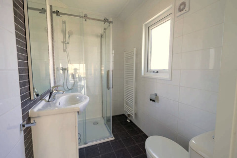 Modern bathroom at Velthorst 4, Zuiderzee, Netherlands, featuring shower, sink, toilet and window.