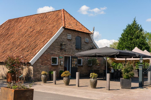 Holiday home with terracotta roof and outdoor seating at Holiday Resort 't Schuttenbelt in Overijssel, Netherlands.